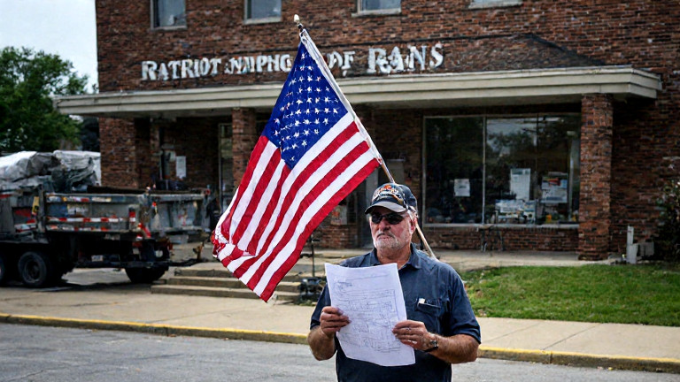 construction worker holding American flag while inspecting blueprint at Vermilion City Hall site