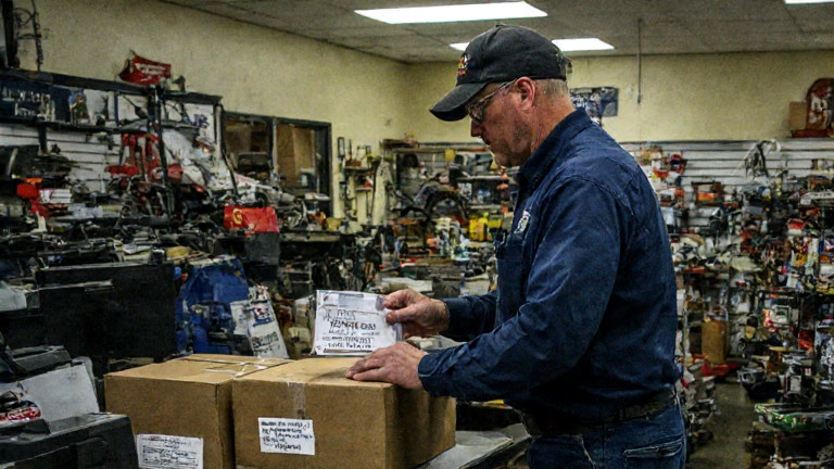 postal worker in uniform carefully stamping a package with "VERMILION FREEDOM" in a small post office lobby