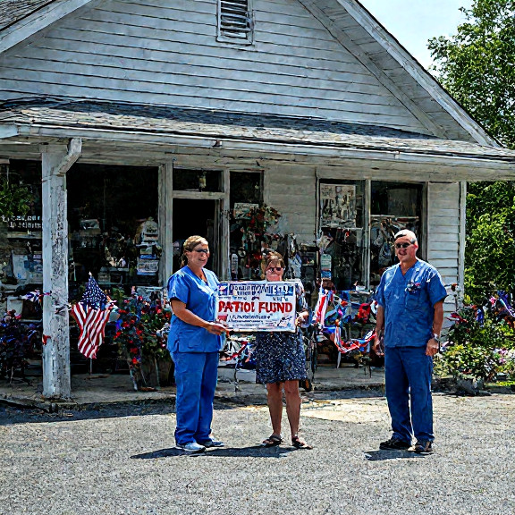 nurse in scrubs holding a "Patriot Fund" donation box outside a Vermilion community center